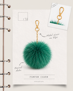 SoulByChi tasarım görseli — Pompom Charm ürün kartı: zümrüt yeşili hacimli form, metal zincir ve klips detayları.